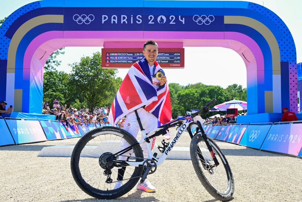 Britain's Thomas Pidcock poses with his gold medal as he celebrates his victory after winning the men's cross-country mountain biking event during the Paris 2024 Olympic Games in Elancourt Hill venue in Elancourt, on July 29, 2024. (Photo by John MACDOUGALL / AFP)