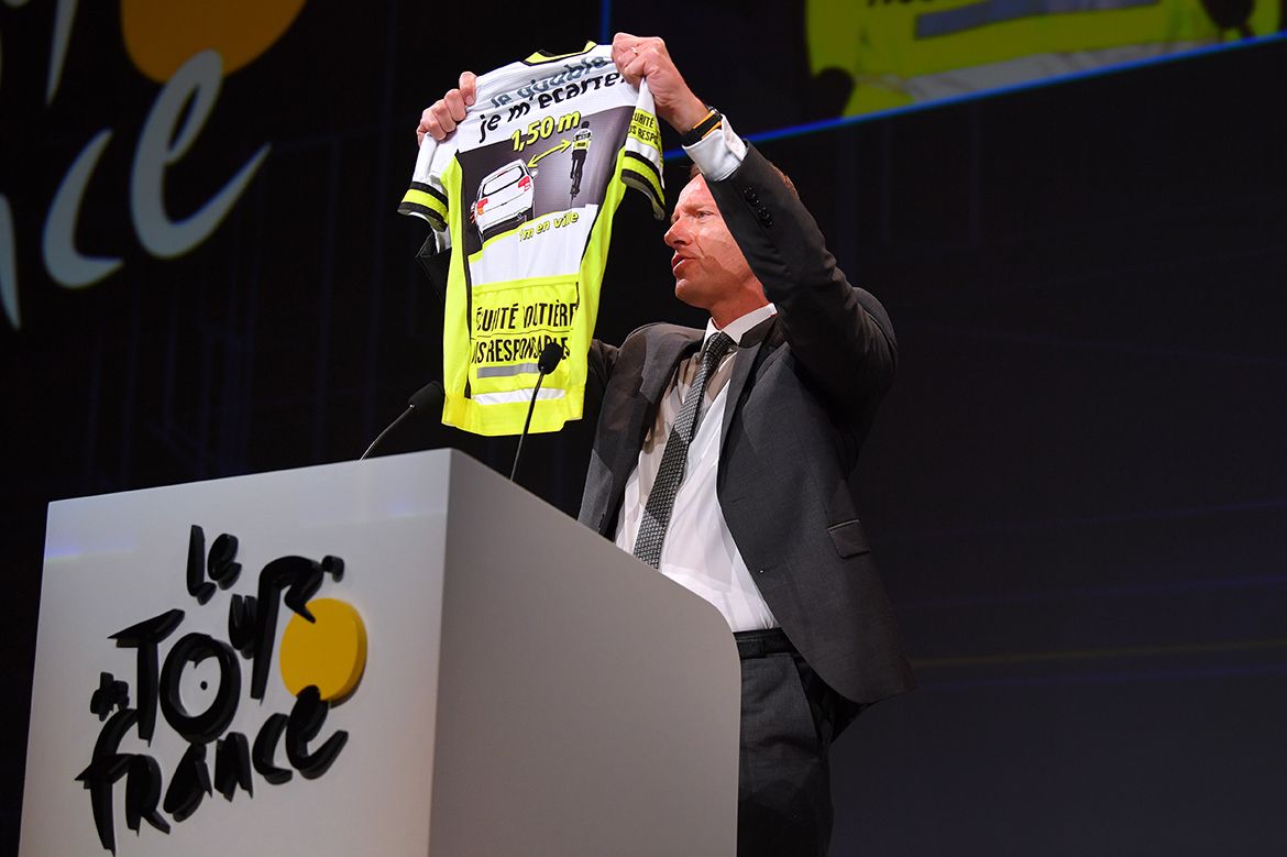 Prudhomme holds up a jersey urging drivers to give cyclists space when overtaking