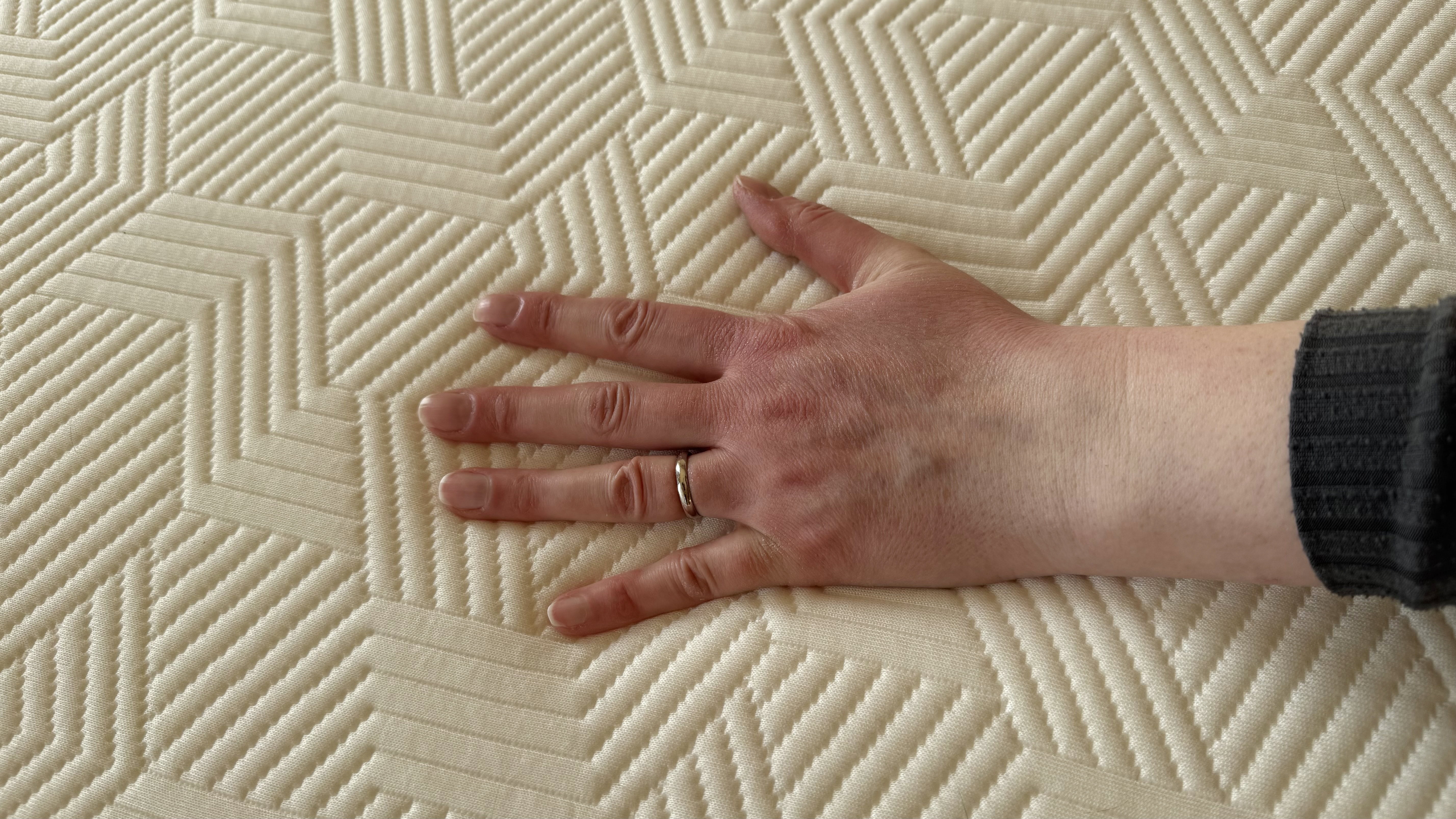 A hand pressing on the Panda Hybrid Bamboo mattress