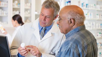 Pharmacist explains prescription to senior man