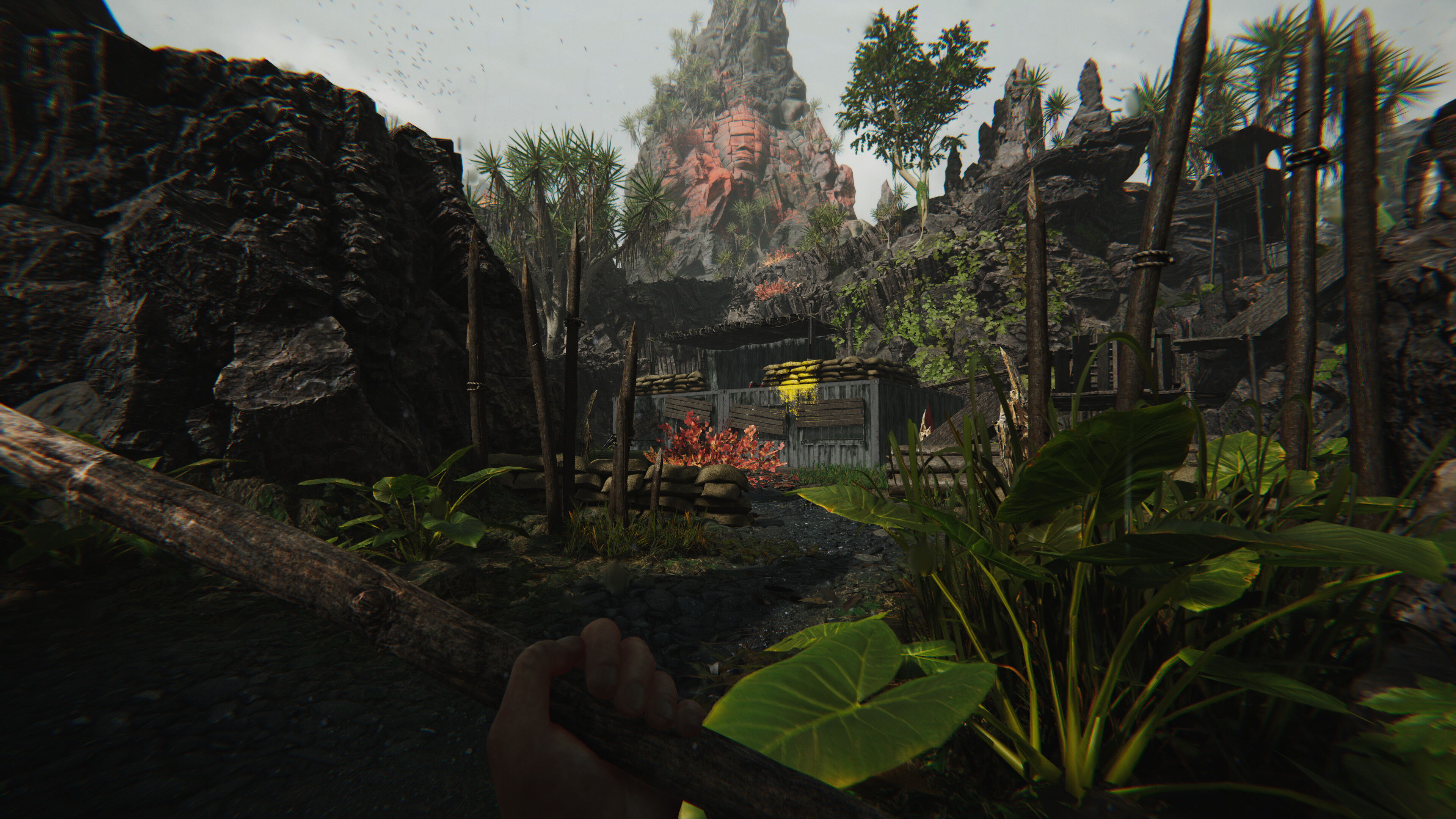 A screenshot of Ferocious that shows the player crouched in shrubbery watching a high-tech military base while holding a spear
