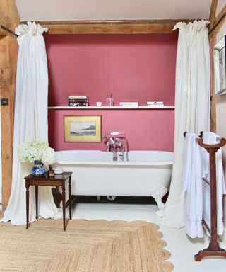 under the eaves bathroom with walls in Rhubarb by Paint and Paper Library and roll top bath in Sarah Vanrenen Wiltshire country barn