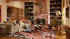 Ruggable x Jungalow rug collab with pink brick fireplace, geometric rugs, decorated shelves, gray sofa, potted plants and Justina Blakeley 