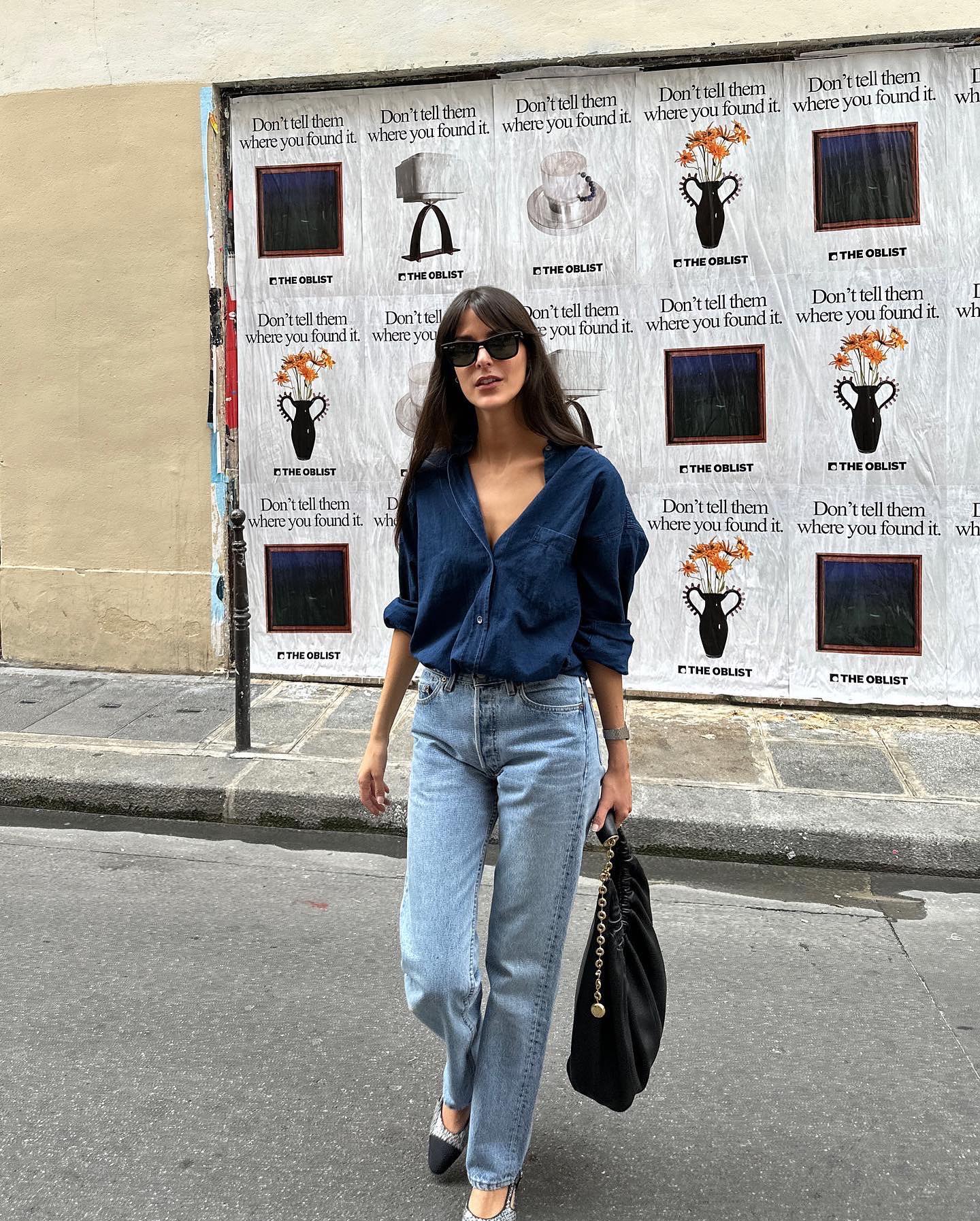 Leia Sfez wearing a navy button-down shirt tucked into baggy jeans with Chanel cap-toe shoes and a Loewe bag.