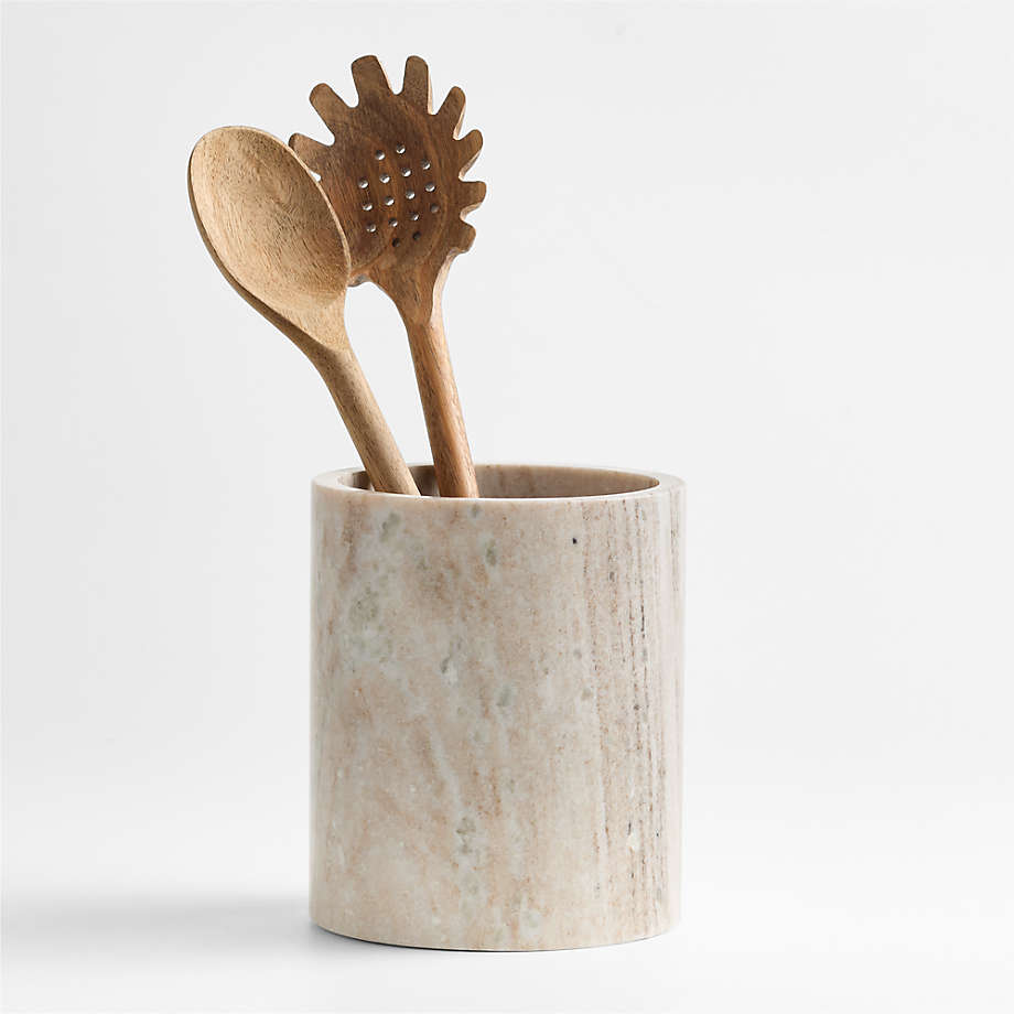 A marble utensil pot with two wooden spoons insde