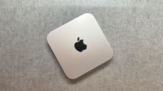 The Mac Mini Pro M2 is mini pc. It's a thin, square shape with rounded corners (20 x 20 x 3.5 cm). It's silver in color and has the Apple logo in the center of it (a black apple with a bite taken out of it).