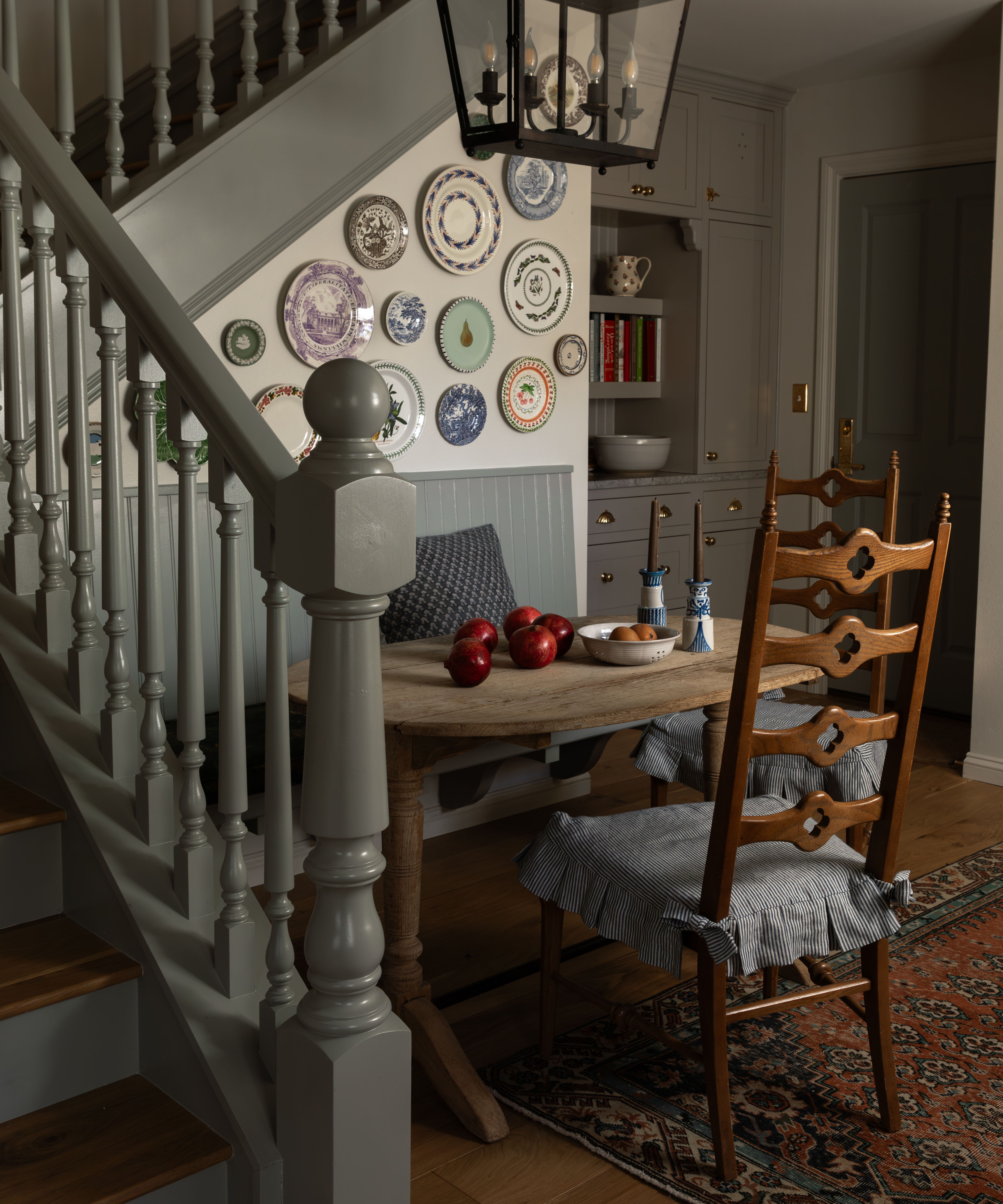 a small home with painted green staircase and a small banquette dining area tucked underneath