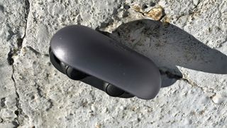 the sony wf-c500 true wireless earbuds in their charging case on a stone surface