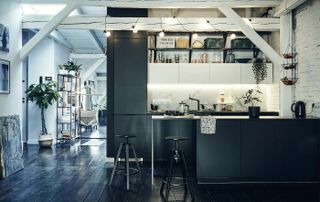 open plan kitchen loft, with a dark kitchen and white open space with beams, and a dark floor