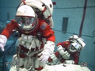 Astronauts Stan Love (left) and Steve Bowen perform a mock asteroid exploration spacewalk underwater while wearing modified versions of the orange launch and entry suits used on space shuttle missions in this still from a NASA video. The aquatic 'spacewalk' aimed to test tools and techniques for NASA's Asteroid Initiative Mission.