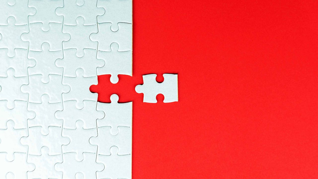 white puzzle with last piece going in on red background