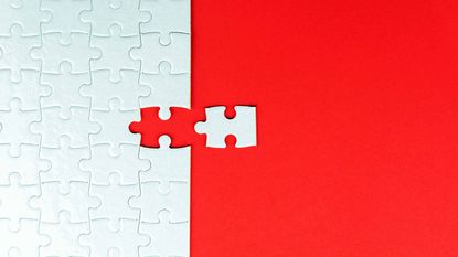 white puzzle with last piece going in on red background