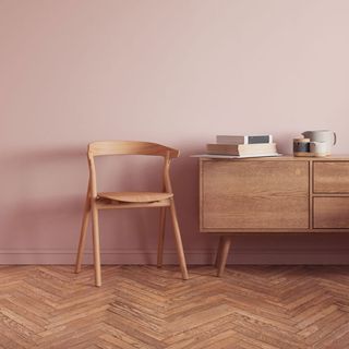 a wooden chair and sideboard in front of a light pink wall, and a wooden pattern floor