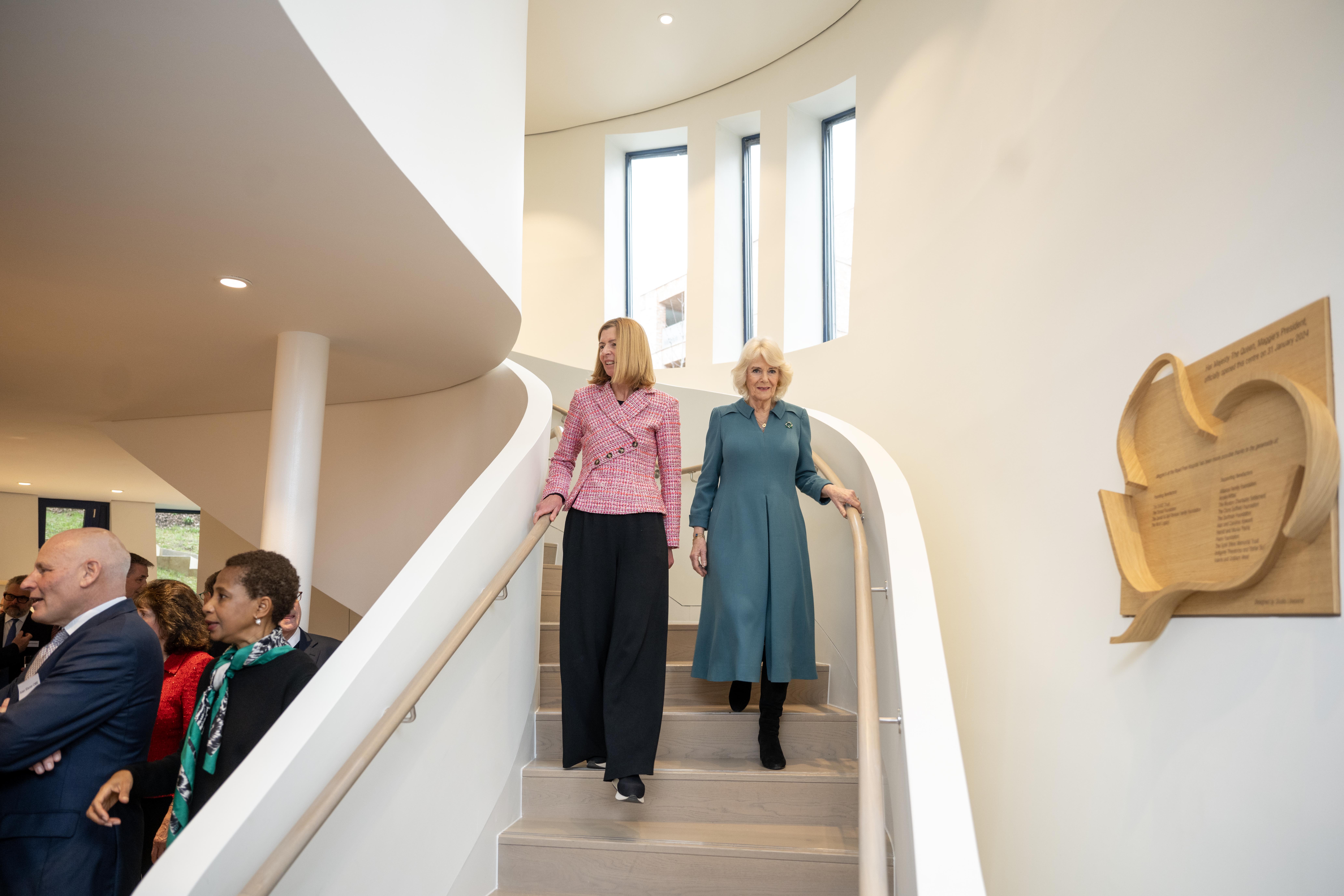 Queen Camilla and Dame Laura Lee walking down a staircase at Maggie's Free