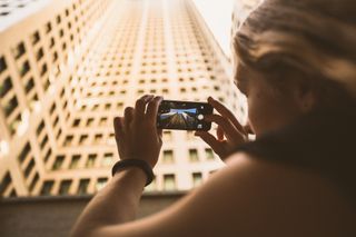 Woman taking photo of a building on her smartphone camera