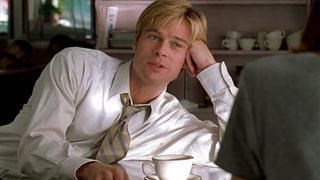 Brad Pitt, wearing a shirt and tie, leans over a counter while drinking coffee in Meet Joe Black