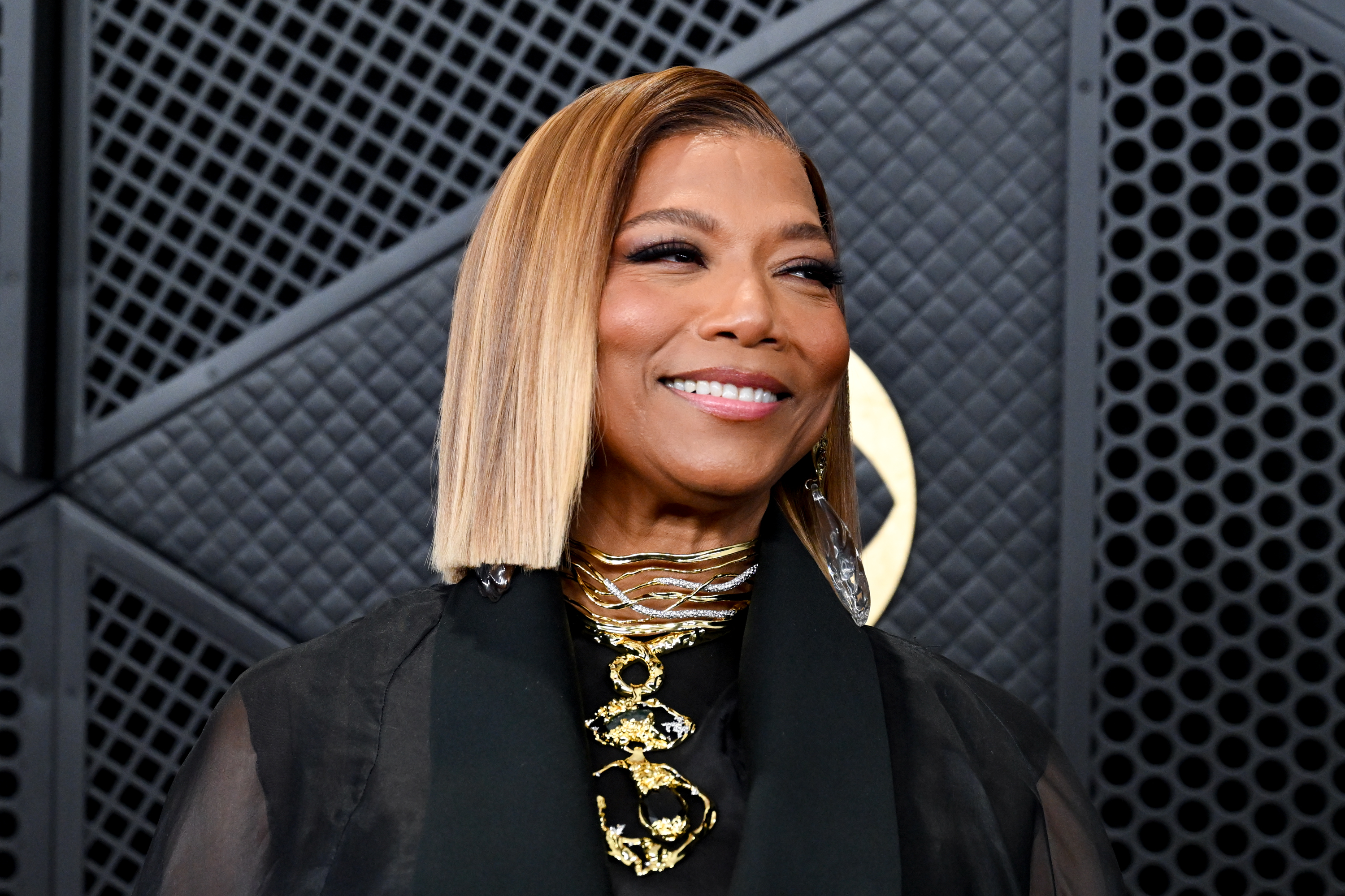 a black woman with blonde hair poses on a red carpet