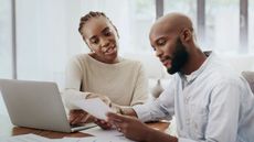 A couple look over their tax return at their dining room table for financial planning purposes.