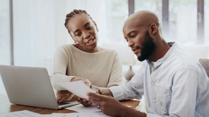 A couple look over their tax return at their dining room table for financial planning purposes.