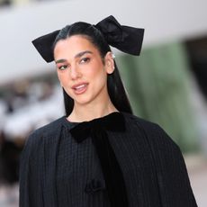 dua lipa wearing all black with a large black hair bow
