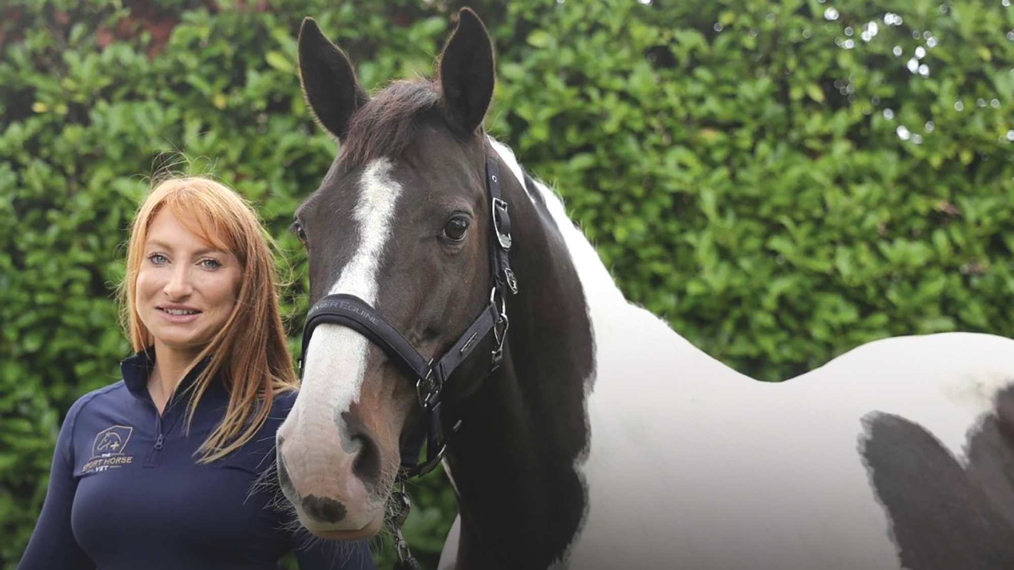 Vet Stephanie Miller stands beside a coloured horse wearing a headcollar