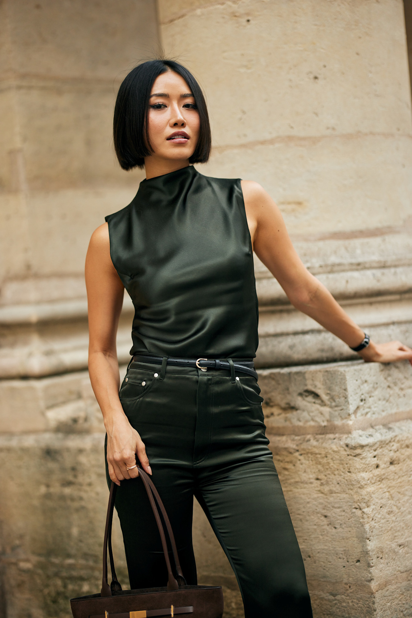 a woman with a dark blunt bob wearing a black top and black jeans