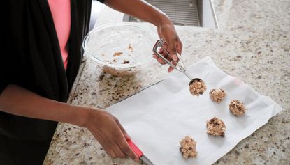 Woman placing cookie dough on baking sheet
