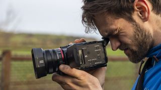 A male photographer looking through the viewfinder of the Panasonic HC-X1500 camcorder