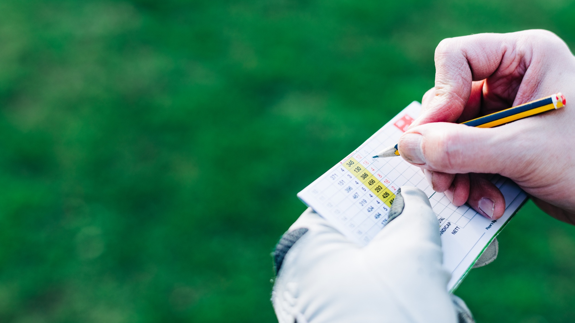 A man marks a score on his golf scorecard.
