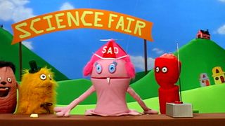 Many puppets at a science fair including one wearing a spinning beanie with the word 'Sad' on it in Wonder Showzen