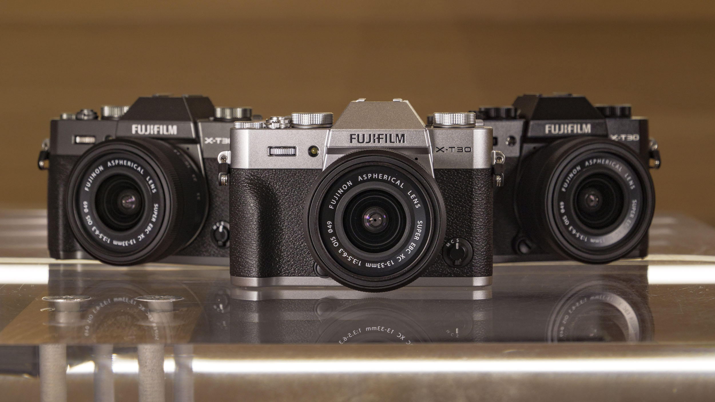 Fujifilm X-T30 III camera in three colors, on a glass table