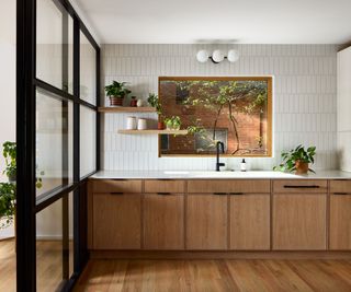 A wood and white kitchen with windows that connect the kitchen to an outdoor space