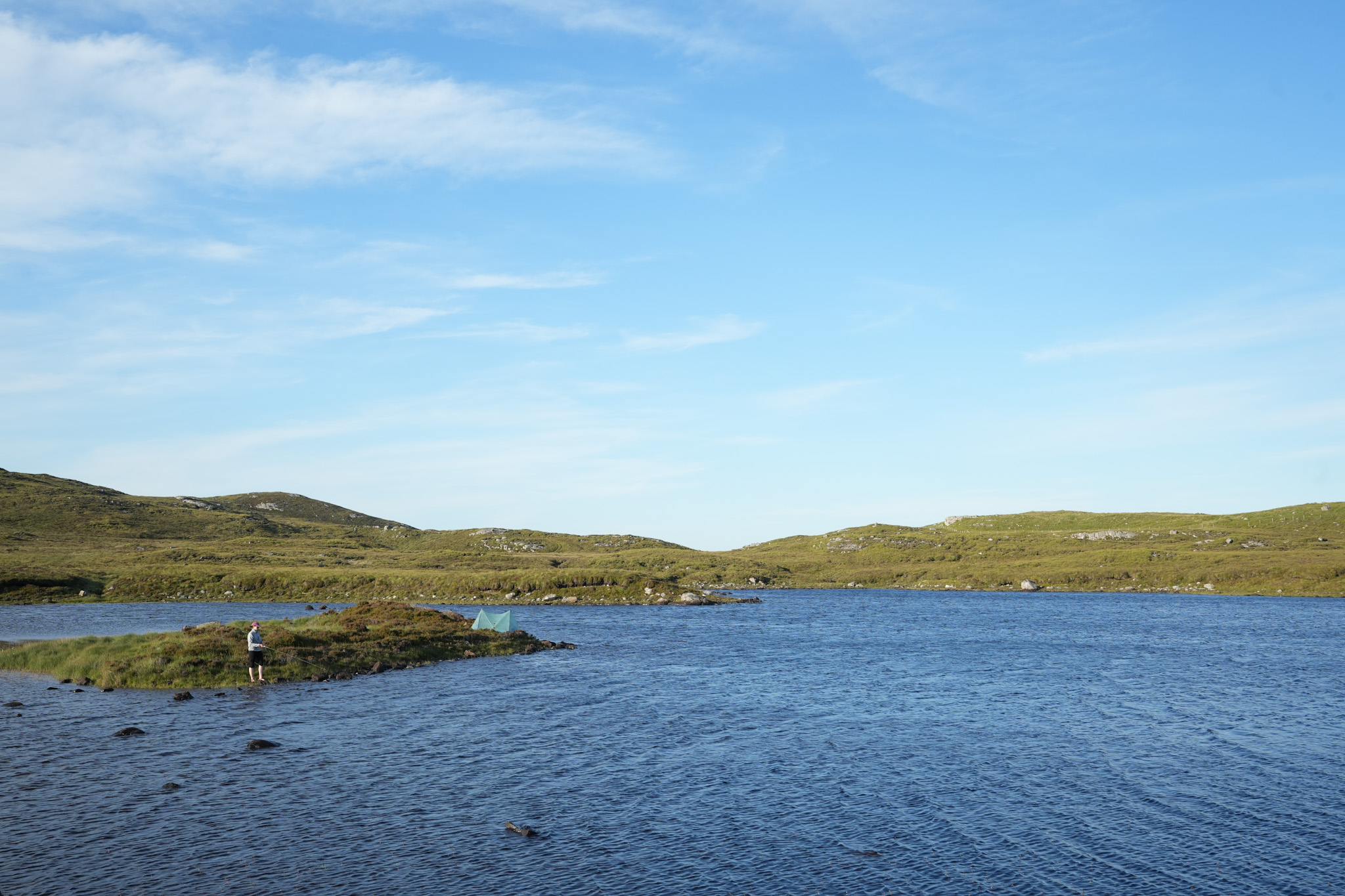 A woman fishing in a beautiful blue loch