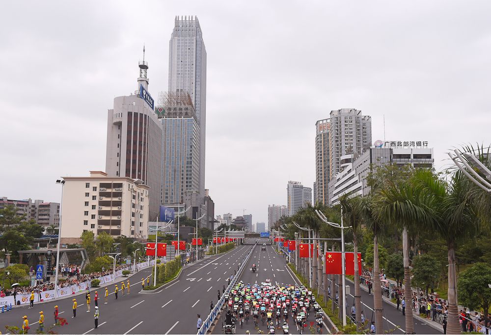 The peloton is dwarfed by the local skyline during stage 3 at the Tour of Guangxi