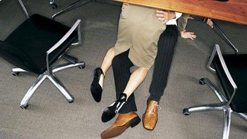 A couple in an embrace under a desk