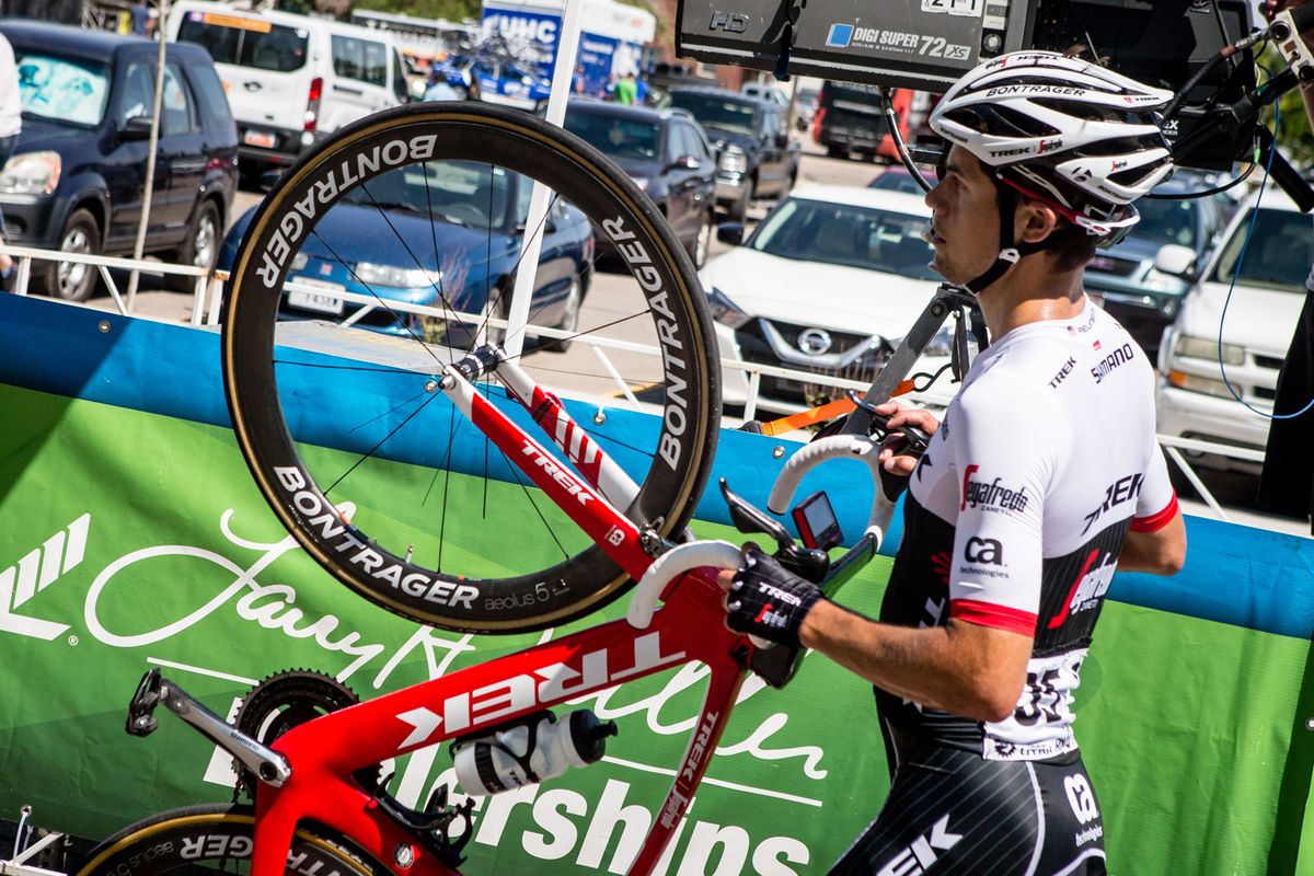 Kiel Reijnen walks his bike across the line during stage 1 of the Tour of Utah after contact with another rider left his front wheel inoperable.