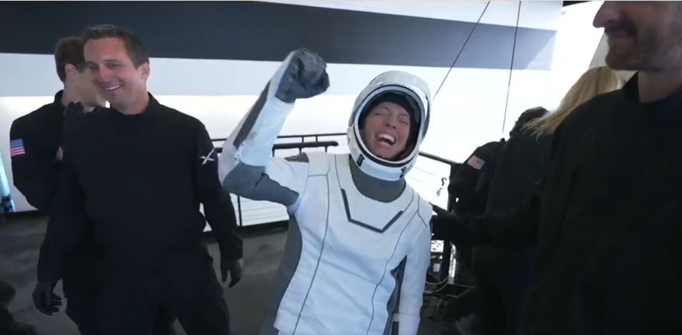 astronauts hold wave aboard a spaceship