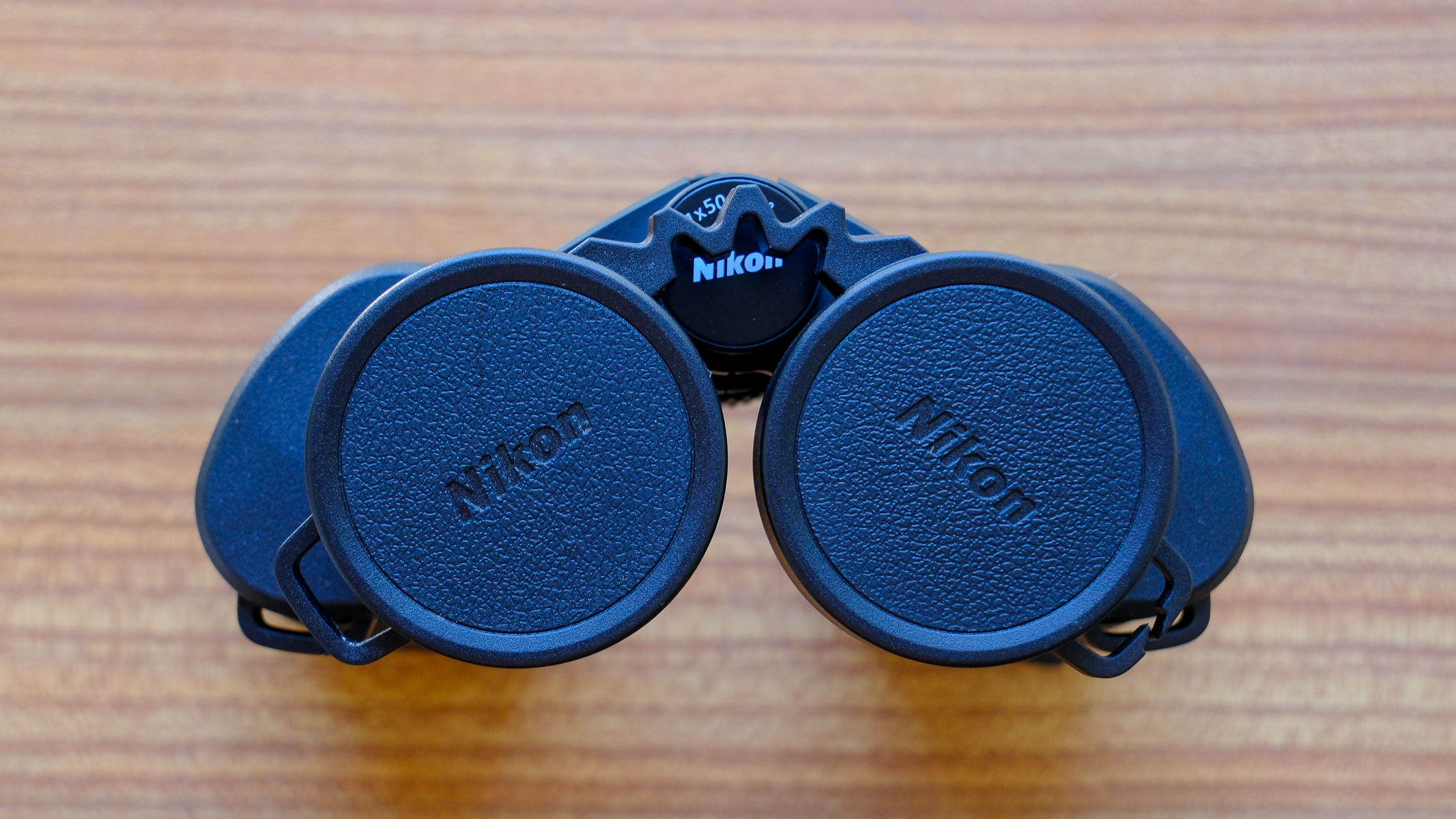 The Nikon Action 7x50 binoculars stood up on a wooden table, with eyecup cover on.