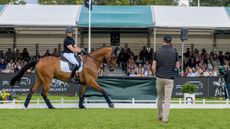 Tom McEwen rides Toledo De Kerser in front of the Burghley crowds with Carl Hester looking on