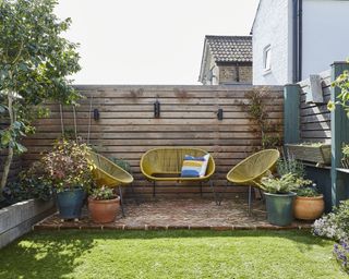 Pallet style garden decking and fence with yellow outdoor sofa and lounge chairs