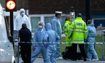 Police and forensic officers work near the scene of the alleged terrorist attack, in which an off-duty British soldier was brutally murdered in broad daylight.