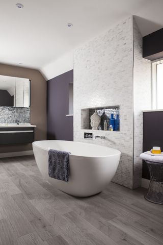 bathroom with modern freestanding bath, tiled feature wall and wooden flooring