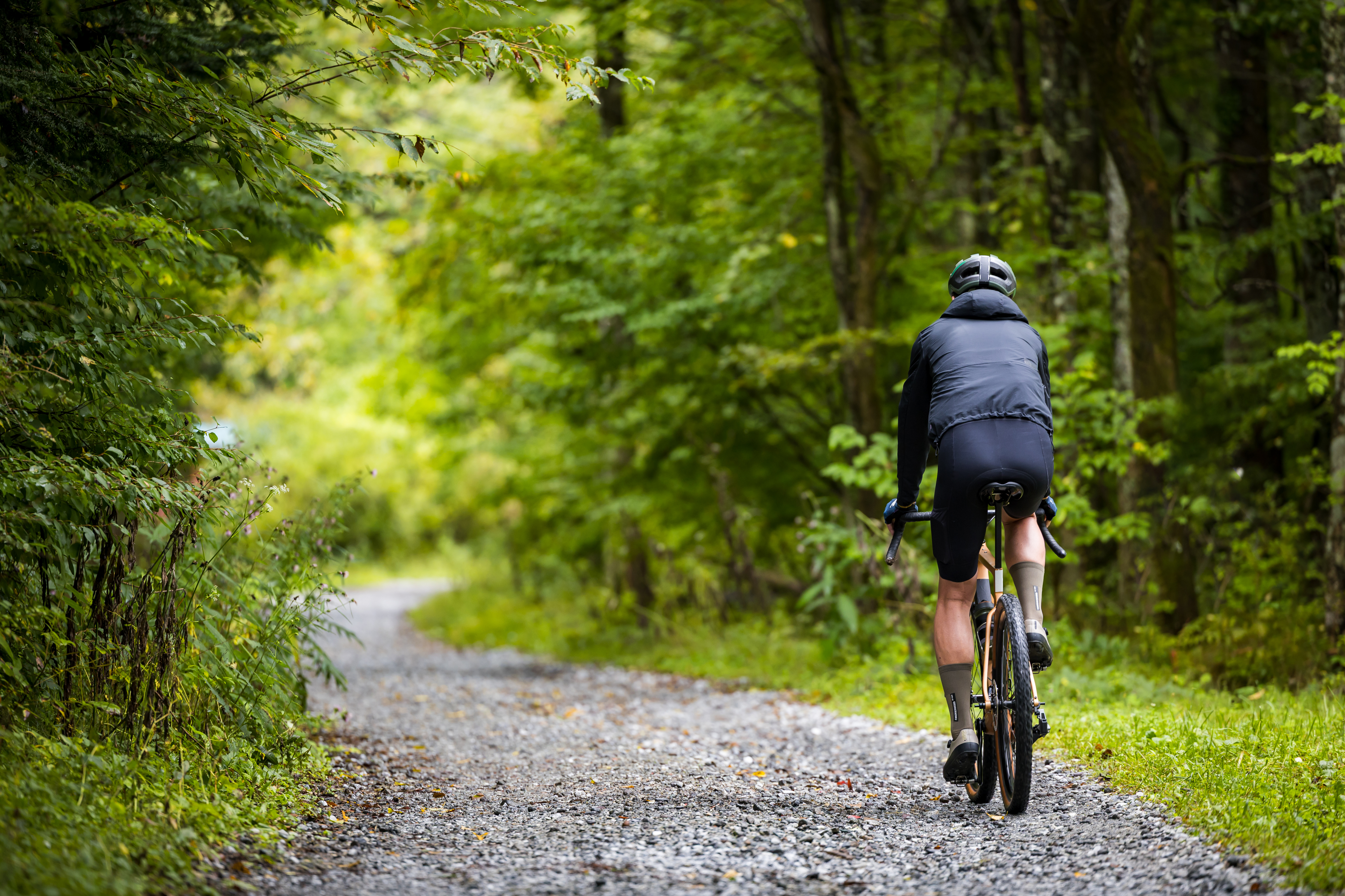 Ciclista andando de bicicleta de cascalho em uma estrada de terra na floresta