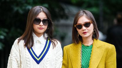 best tinted lip balms - two women wearing sunglasses stood next to each other both with washes of colour on their lips - Getty images - 1342957857