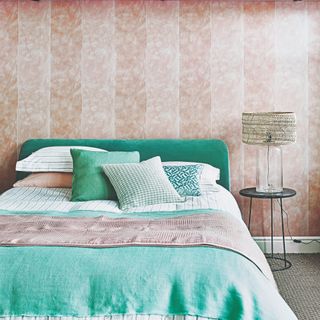 A pink bedroom with a turquoise velvet headboard on a bed