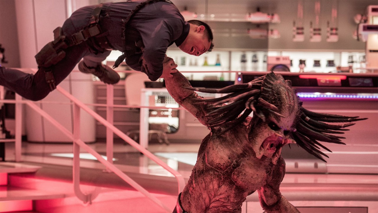 Still from the movie The Predator.  Here we see Predator throwing a guard to the ground inside a high-tech laboratory.