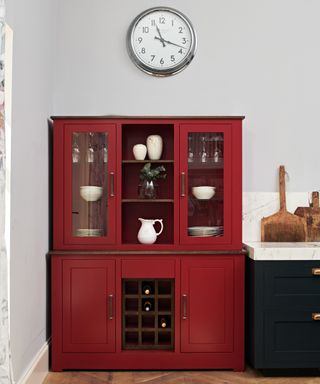 red dresser in kitchen with pale grey walls and dark blue units