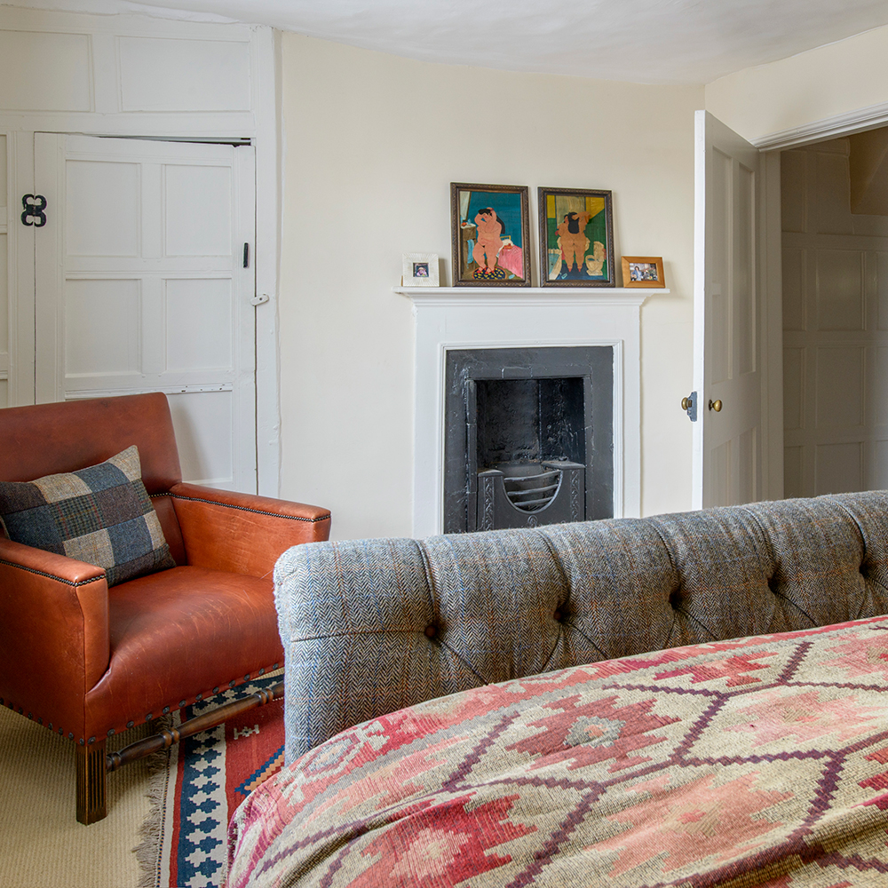 bedroom with cream colour wall grey bed and brown sofa chair