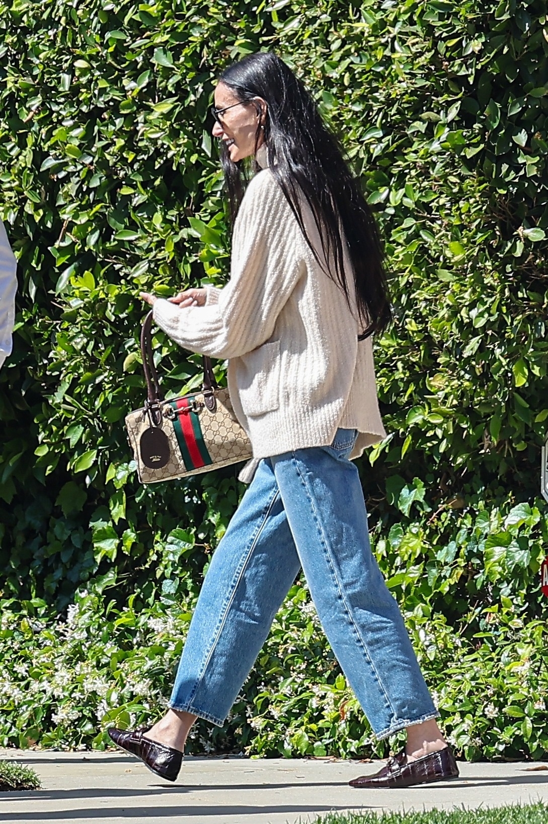 Demi Moore wears a cardigan, a gucci bag, jeans and eel-leather flats,