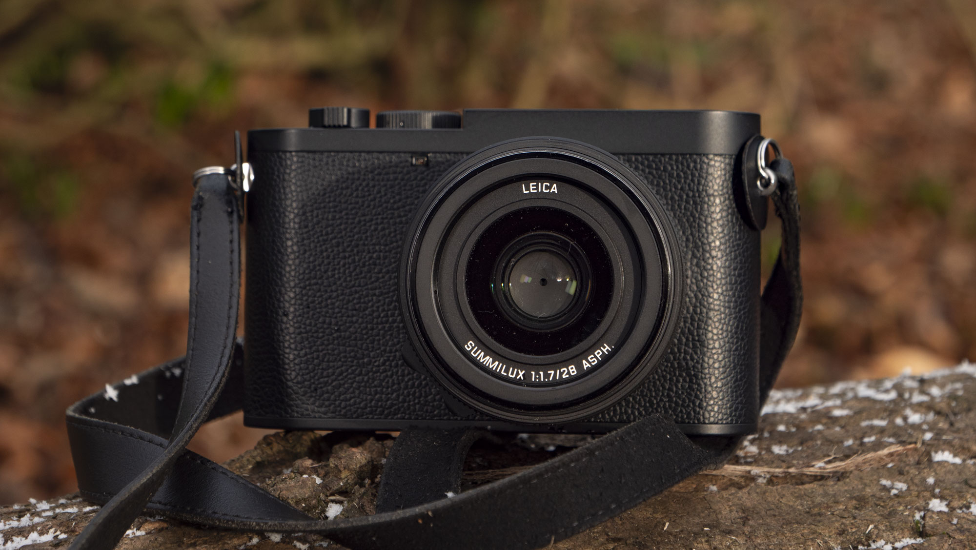 Leica Q3 Monochrom compact camera outside on a snow-dusted log